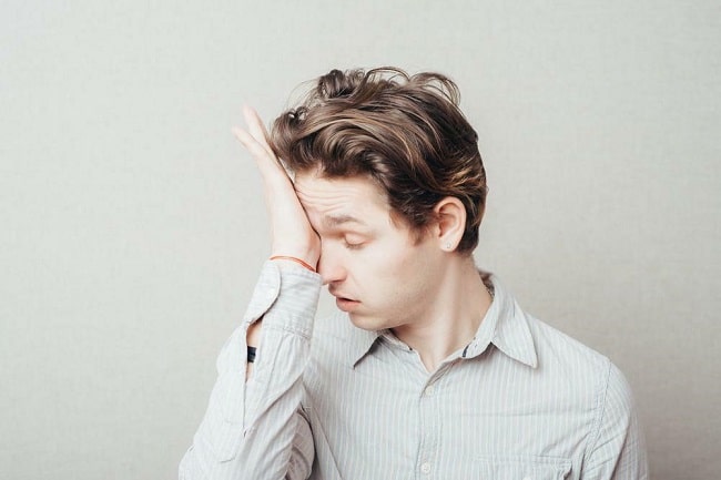 An upset child with his hand over his eyes.