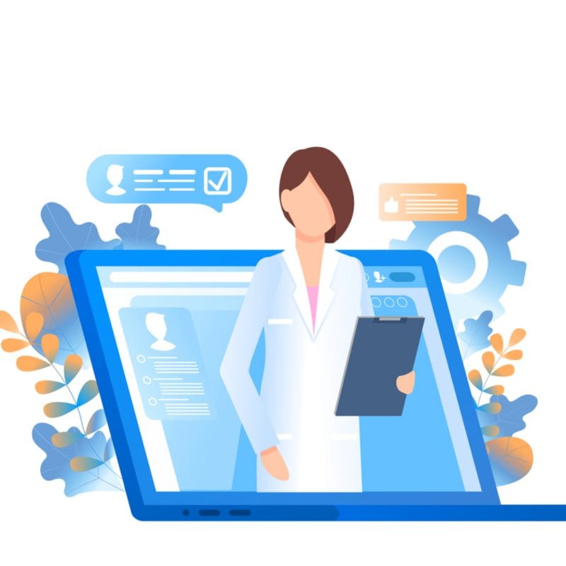 A physician with a clipboard in her hand, standing by a laptop.