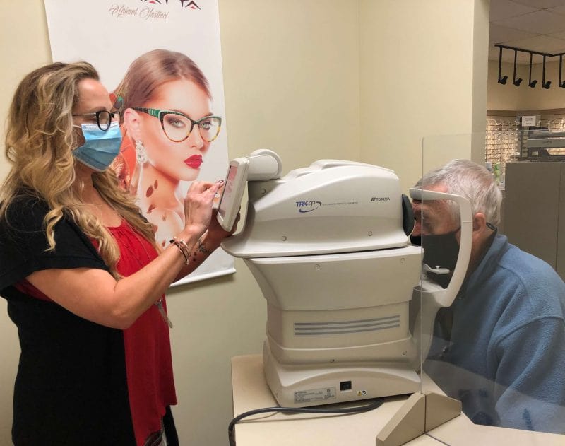 Woman in mask having her eyes examined by a machine.