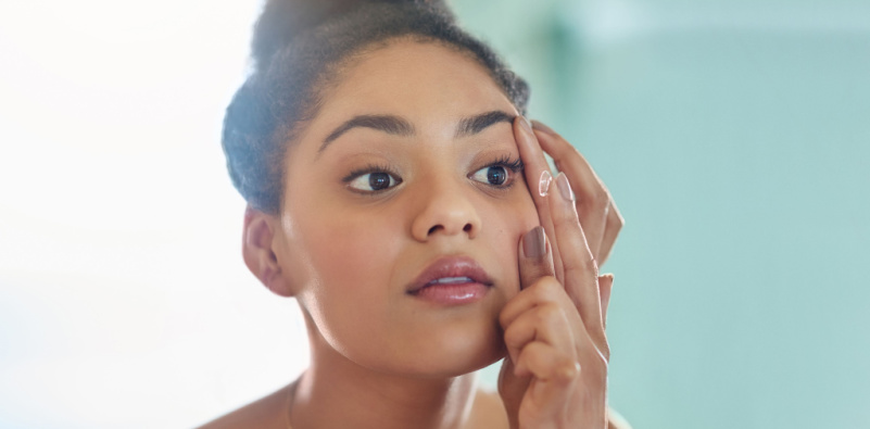 A woman examining her reflection in a mirror, emphasizing the importance of good contact lens hygiene