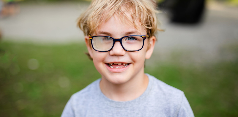 A young boy with glasses on, smiling happily