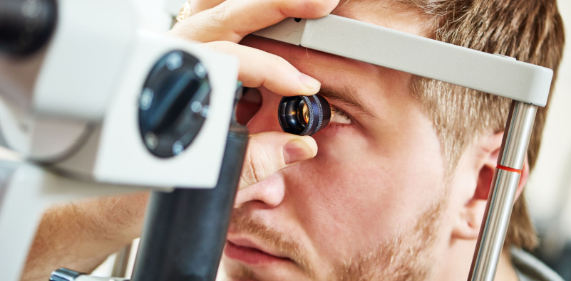 A man undergoing an eye exam, focusing on the chart in front of him to assess his vision