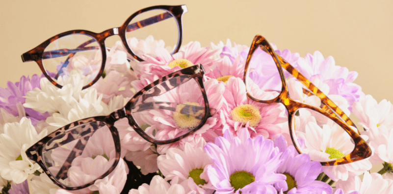 Three pairs of glasses on top of a colorful flower arrangement.