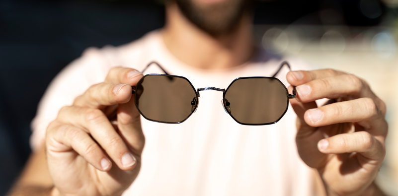 Someone holding up a pair of polarized sunglasses