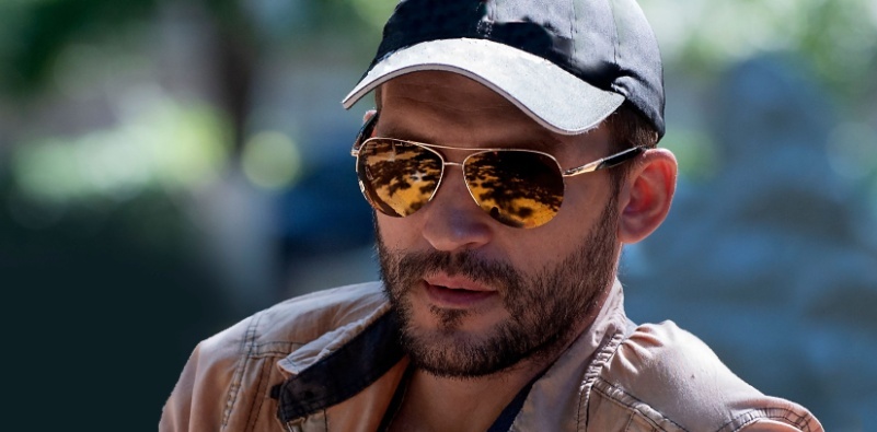 man wearing a cap and brown tinted mirror aviator sunglasses