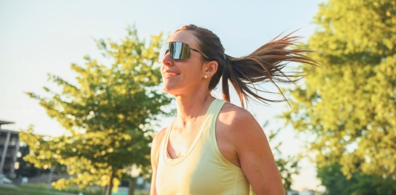 A woman running outside wearing sports sunglasses