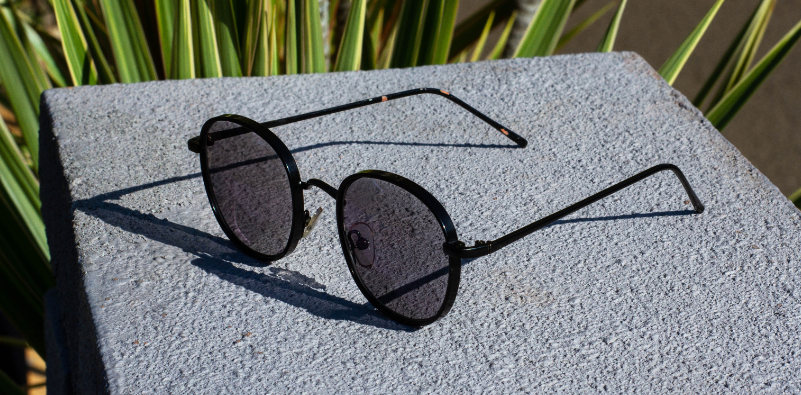 Black photochromic glasses resting on a stone surface.